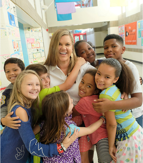 Principal hugging students in hallway of a school